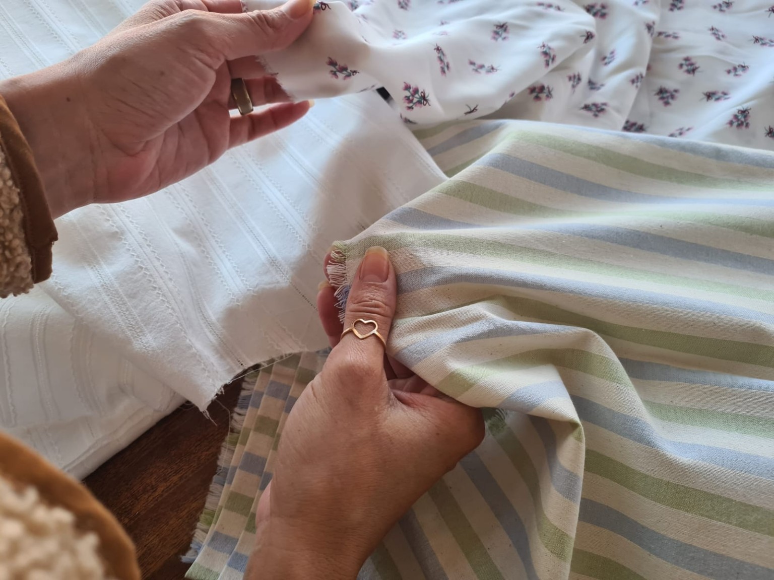 Mãos comparando tecidos de superfícies, espessuras e bordas diferentes